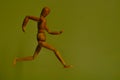 Wooden running man in front of an exotic green wall