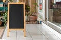 Wooden rustic blackboard in front of restaurant entrance. Mock up Menu Blank Blackboard sign stand Shop Cafe Restaurant. Street Ma Royalty Free Stock Photo