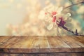 Wooden rustic table in front of spring white cherry blossoms tree. vintage filtered image. product display and picnic concept