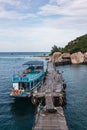 Wooden sailboat docked in a tranquil ocean with a rocky shoreline in the background Royalty Free Stock Photo