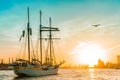 Wooden sailboat sailing toward dramatic sunset beginning new travel adventure with flying bird Royalty Free Stock Photo