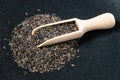 Wooden scoop on pile of niger seeds on black