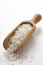 Wooden scoop with polished long rice grains on white background
