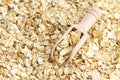 Wooden scoop of raw rolled oat flakes top view