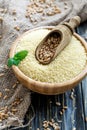 Wooden scoop with wheat in a bowl with couscous.