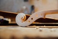 Wooden scroll detail of the head of the violin. Raw wood, texture. Against the background of workshop. Royalty Free Stock Photo