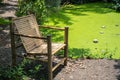 Wooden seat bamboo chair beside the natural green pond for relaxation vibe outdoor of home garden design decoration Royalty Free Stock Photo