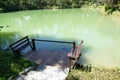 Wooden seat on the pier and the fish in the pond