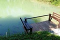 Wooden seat on the pier and the fish in the pond