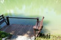 Wooden seat on the pier and the fish in the pond