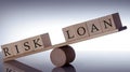 Wooden seesaw representing imbalance between RISK and LOAN isolated over black background