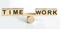 Wooden seesaw representing imbalance between TIME and WORK isolated over white background