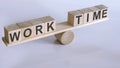 Wooden seesaw representing imbalance between WORK and TIME isolated over white background