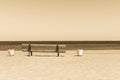 Wooden sepia bench on the sandy beach seashore