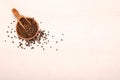 Wooden serving spoon shovel full of black pepper spice balls in wooden bowl isolated over the white background. Copy space Royalty Free Stock Photo