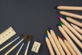 Wooden set of colored pencils, sharpener, brushes and ruler on black background Royalty Free Stock Photo