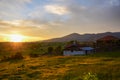 Wooden shack, blue skies, and green fields with vibrant clouds it dawn,