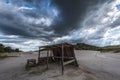 Wooden shack with dramatic clouds and sunbeam in background Royalty Free Stock Photo