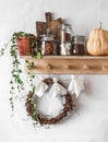 Wooden shelf with cans of cocoa, cookies, marshmallows,pumpkin, wreath, flower and homemade garland Halloween paper ghosts from