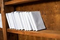 Wooden shelf is filled with books in white paper covers Royalty Free Stock Photo