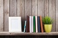 Wooden shelf with photo frames, books and plant Royalty Free Stock Photo