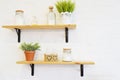 Wooden shelves on white brick wall texture background with vintage bottles and vases of flowers Royalty Free Stock Photo