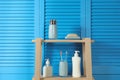 Wooden shelving unit with toiletries near blue folding screen. Bathroom interior element