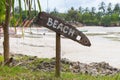 Wooden sign Beach on tropical coast. Low tide landscape with signpost Beach. Beach with palm trees and boats. Paradise direction. Royalty Free Stock Photo