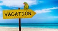 Wooden sign on beautiful beach and clear sea wit text vacation. A green parrot sits on a pointer to a tropical paradise Royalty Free Stock Photo