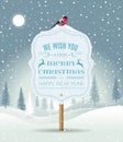 Wooden sign board with Christmas greeting on winter landscape with snow-covered forest and bullfinch. Holiday winter Royalty Free Stock Photo