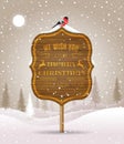 Wooden sign board with Christmas greeting on winter landscape with snow-covered forest and bullfinch. Holiday winter Royalty Free Stock Photo