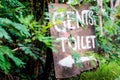 Wooden sign for gents toilet in bushes