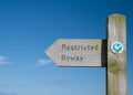 A wooden sign points the way of a restricted byway in the UK - a route over which the public have restricted rights