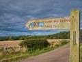 A wooden sign post points the way of the Coast and Castles cycle route and Northumberland Coast Path. Royalty Free Stock Photo