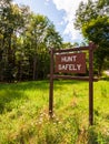 A wooden sign saying HUNT SAFELY on the side of a road in Warren county, Pennsylvania, USA