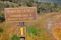 Wooden sign showing the Paseo de la Isla walking trail in Tierra del Fuego National Park, surrounded by green, brown and