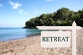 Wooden sign with word Retreat and beautiful view of beach and forest Royalty Free Stock Photo