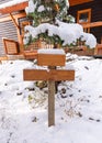 Wooden signboard post with snow covered or guidepost on front of wooden house