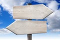 Wooden signpost with two arrows, sky in background Royalty Free Stock Photo