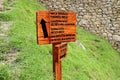 Wooden signpost to the INKA BRIDGE, GUARDHOUSE, SUN GATE and WAYNAPICCHU MOUNTAIN in the archaeological site of Machu Picchu Royalty Free Stock Photo