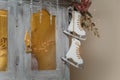 Wooden skates toy hanging on cupboard decorated with fir branches, icycles and snowy roses. merry Christmas decorated elements