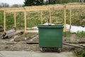Wooden skeleton or frame of a greenhouse in a allotment garden with a bin for organic waste in the foreground