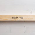 Wooden slat with a Thank you sign on it placed over simple wooden background