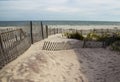 A wooden slated sand fence is partly buried in an ocean beach dune. Royalty Free Stock Photo