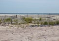 A wooden slated sand fence is partly buried in an ocean beach dune. Royalty Free Stock Photo