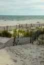 A wooden slated sand fence is partly buried in an ocean beach dune. Royalty Free Stock Photo