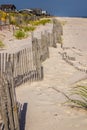 A wooden slated sand fence is partly buried in an ocean beach dune. Royalty Free Stock Photo