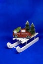 Wooden sledge, toy car with christmas tree isolated on blue background.christmas flat lay with festive decoration Royalty Free Stock Photo