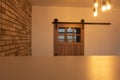 Wooden sliding door with vintage fittings, unusual concrete light fixture and brick wall. Loft interior Royalty Free Stock Photo