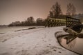 Wooden small bridge on a frozen lake on a frosty winter evening Royalty Free Stock Photo